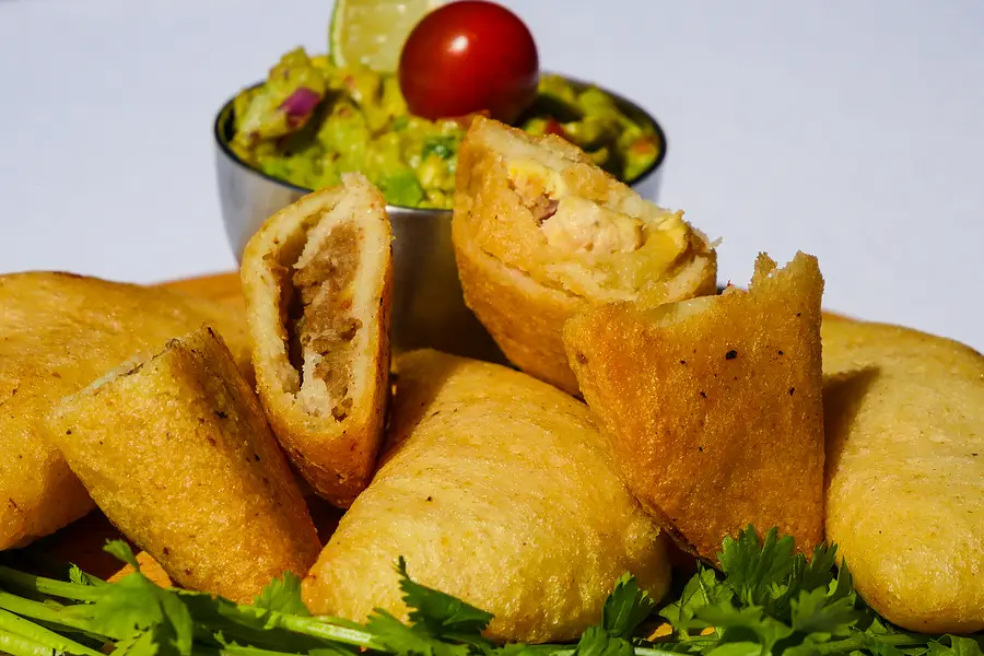 Une pile d'empanadas et un pot de guacamole