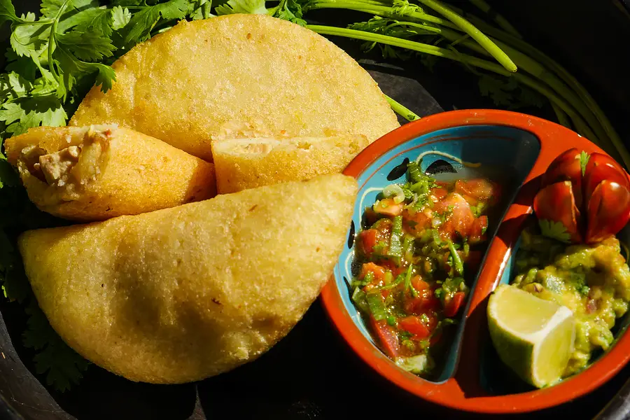 Une grande empanada dorée avec du pico de gallo et du guacamole